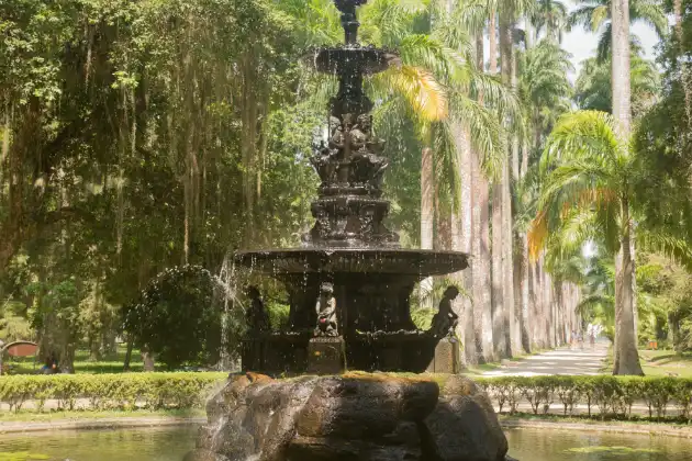 Fonte clássica em meio à vegetação exuberante e palmeiras majestosas no tranquilo Jardim Botânico do Rio de Janeiro.