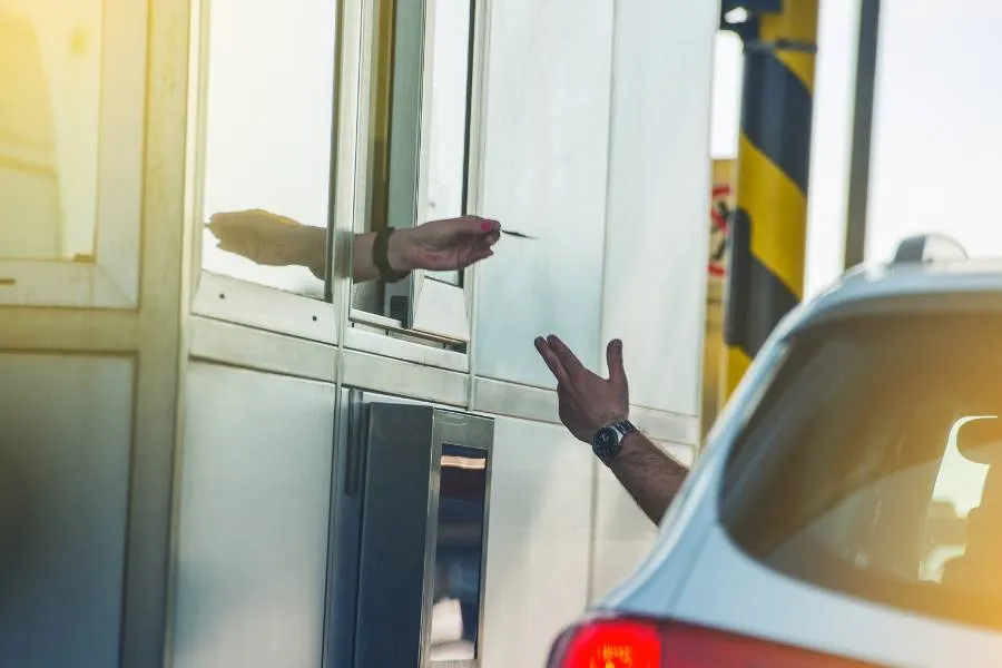 Pagamento de pedágio: motorista entregando cartão em cabine.