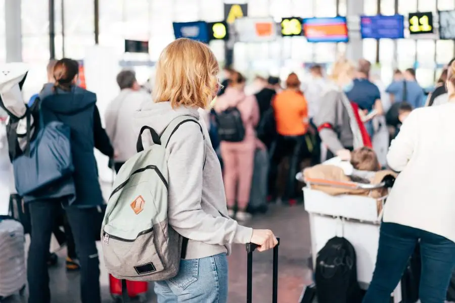 Planejando a viagem: passageira consultando aguardando para fazer check-in aéreo