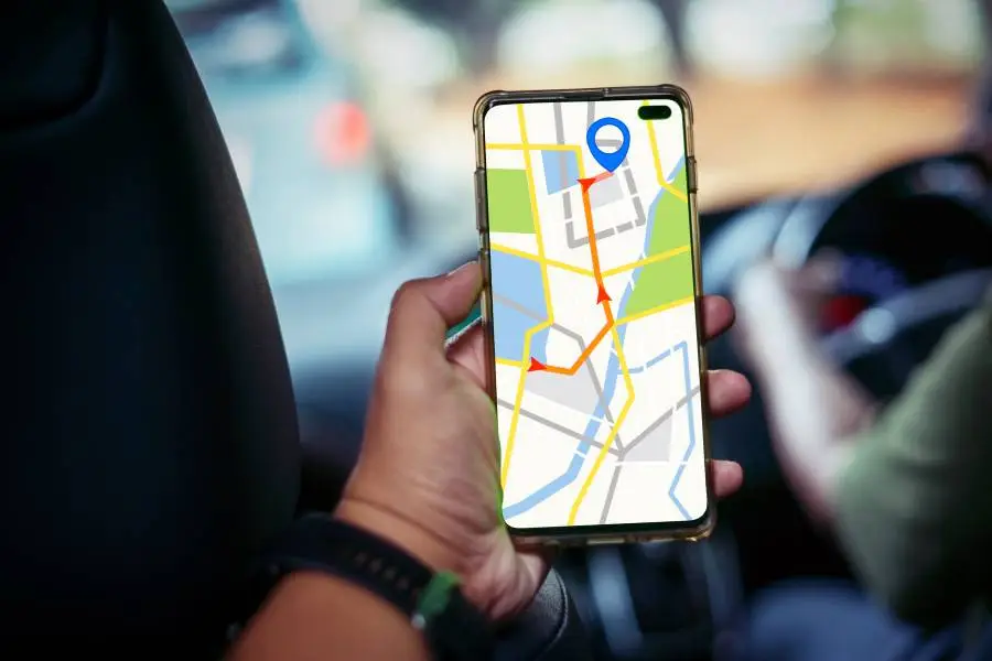 Pessoa em carro usando aplicativo de GPS no celular para encontrar rota offline.