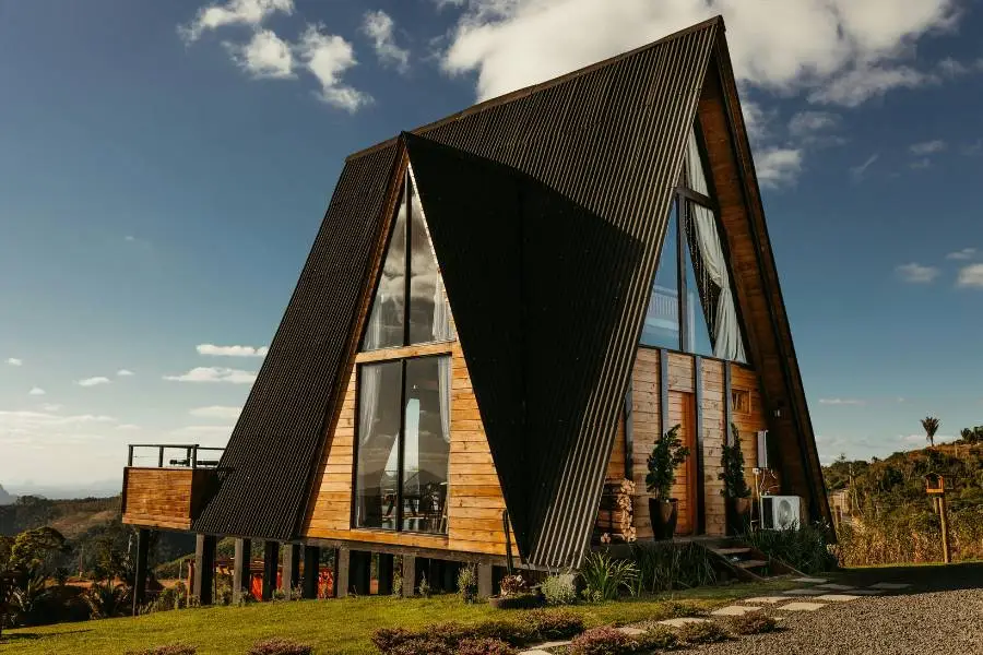 Linda cabana triangular de madeira com telhado preto em meio à natureza exuberante de Minas Gerais.